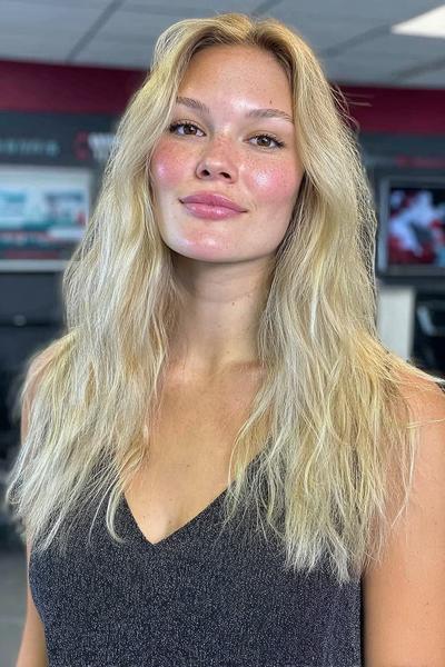 Eine Frau mit langen, welligen Haaren im aschblonden Balayage-Stil.
