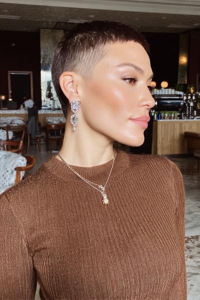 Eine Frau mit einem sehr kurzen Pixie Cut, bei dem die Seiten und der Hinterkopf extrem kurz rasiert und das Deckhaar etwas länger gelassen ist.