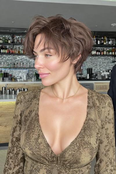 Eine Frau mit einem modernen, platinblonden Pixie Cut mit seitlichem Pony und leicht texturierten Spitzen.