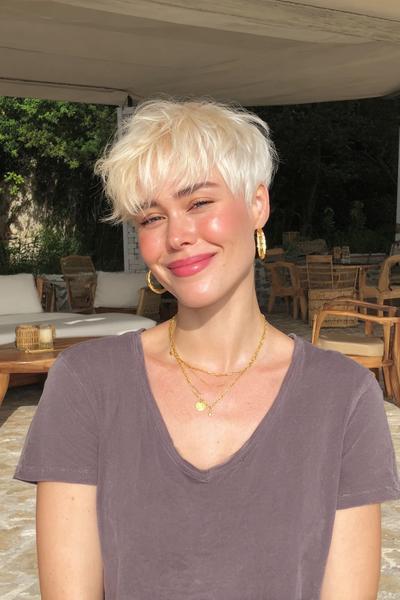 Frau mit einem modernen, mehrschichtigen Pixie Cut mit sanften Wellen und ponyartigem Stirnfransen.