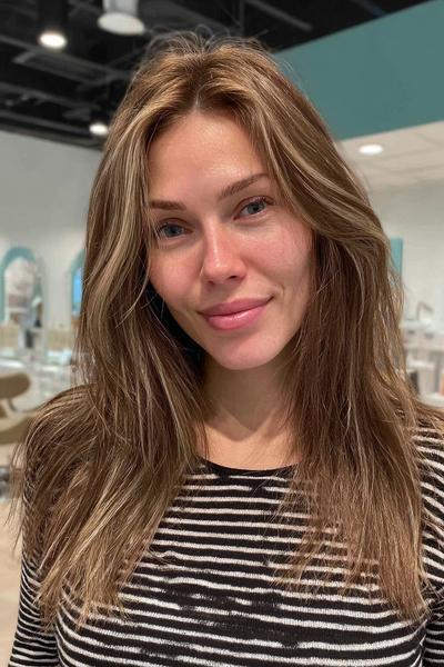 Eine Frau mit mittellangen, im Balayage-Stil gefärbten aschblonden Haaren und sanften Wellen.
