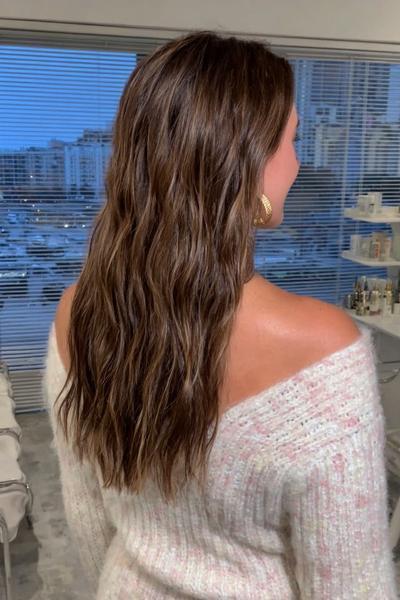 Eine Frau mit dunkelblondem, welligem Haar trägt offene, natürliche Beach Waves.