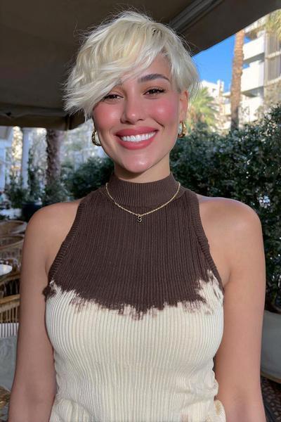 Eine Frau mit einem modernen, kinnlangen Pixie Cut mit fransigem Pony und platinblonden Haaren.