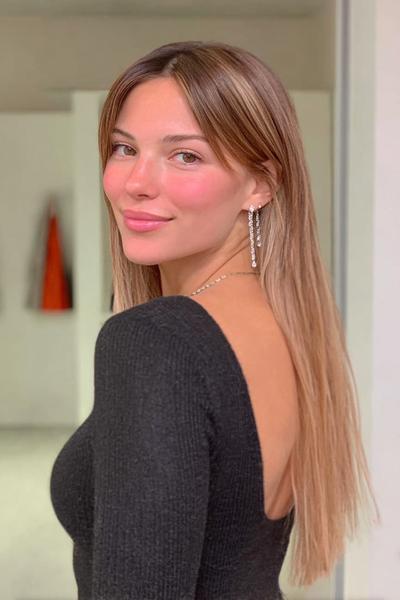Eine Frau mit langen, dunkelblonden Haaren trägt einen Mittelscheitel und glatte Haare, die locker über den Rücken fallen.