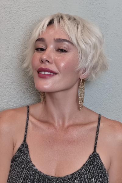 Eine Frau mit einem modernen, platinblonden Pixie Cut mit weichen, unregelmäßigen Fransen und leicht gewellter Textur.