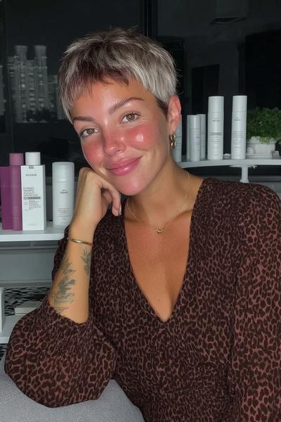 Eine Frau mit einem platinblonden, seitlich gescheitelten Pixie-Cut mit lockerer, fransiger Stirnpartie.