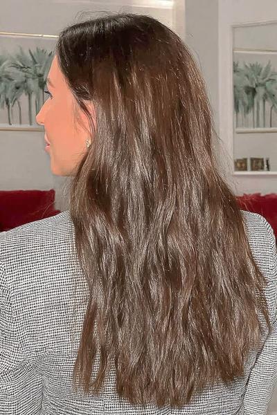 Eine Frau mit langen, mittellangen braunen Haaren trägt ihre Haare offen und natürlich fallend.