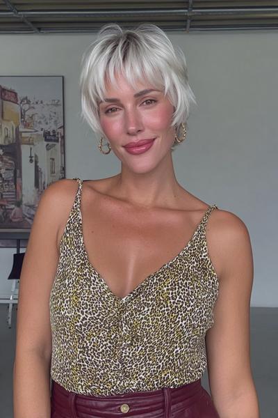Eine Frau mit einem modernen, kurzen, blonden Pixie-Cut mit fransigem Pony.