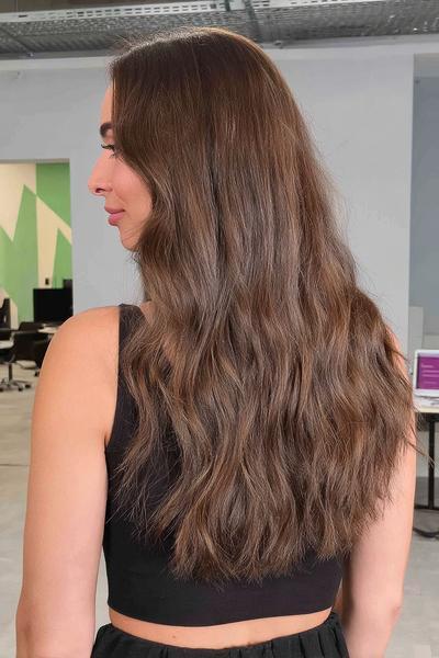 Eine Frau mit langen, leicht gewellten, braun-blonden Haaren trägt ihre Haare offen über die Schultern.